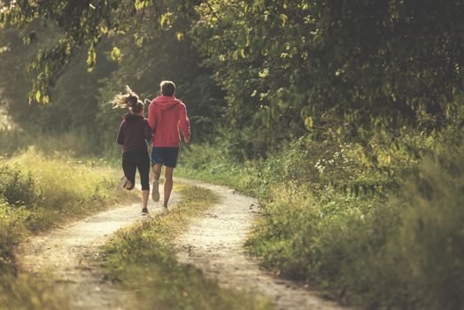 young couple enjoying in a healthy lifestyle while jogging along a country road, exercise and fitness concept