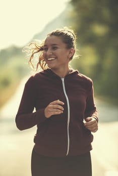 young woman enjoying in a healthy lifestyle while jogging along a country road, exercise and fitness concept