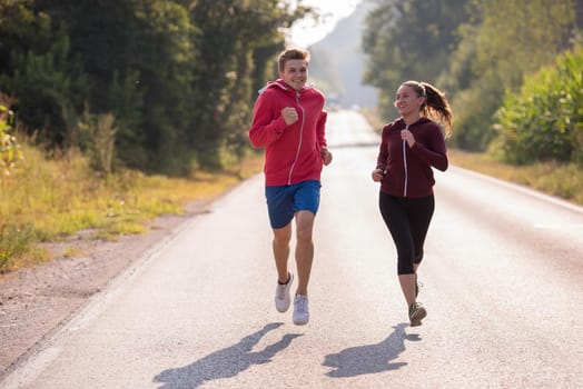 young couple enjoying in a healthy lifestyle while jogging along a country road, exercise and fitness concept