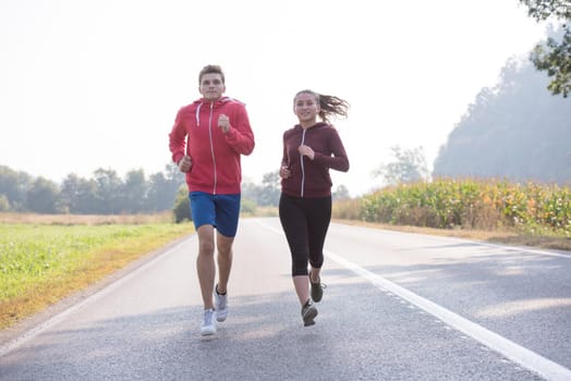 young couple enjoying in a healthy lifestyle while jogging along a country road, exercise and fitness concept