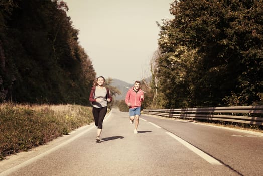 young couple enjoying in a healthy lifestyle while jogging along a country road, exercise and fitness concept