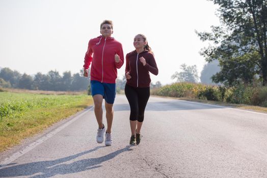 young couple enjoying in a healthy lifestyle while jogging along a country road, exercise and fitness concept