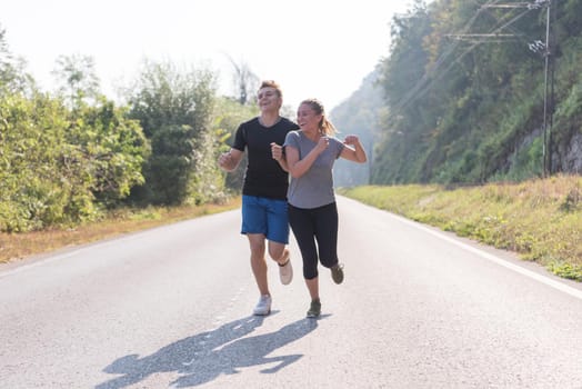 young couple enjoying in a healthy lifestyle while jogging along a country road, exercise and fitness concept