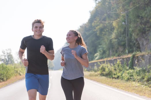 young couple enjoying in a healthy lifestyle while jogging along a country road, exercise and fitness concept