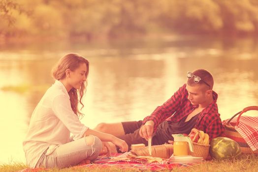 Couple in love enjoying picnic time drink and food in beautiful nature on the river bank