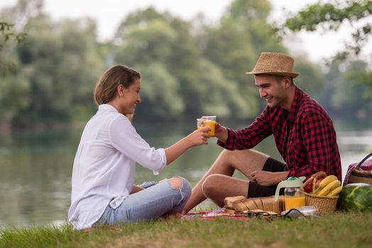 Couple in love enjoying picnic time drink and food in beautiful nature on the river bank