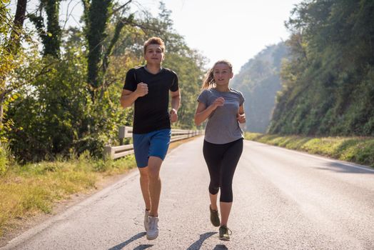 young couple enjoying in a healthy lifestyle while jogging along a country road, exercise and fitness concept