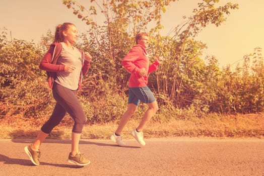 young couple enjoying in a healthy lifestyle while jogging along a country road, exercise and fitness concept