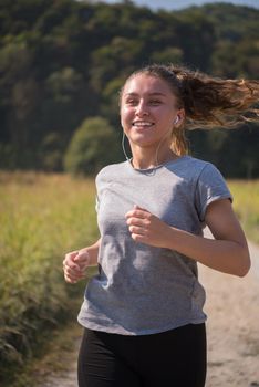 young woman enjoying in a healthy lifestyle while jogging along a country road, exercise and fitness concept