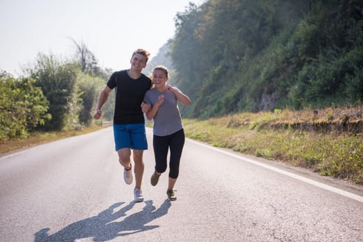 young couple enjoying in a healthy lifestyle while jogging along a country road, exercise and fitness concept