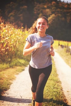 young woman enjoying in a healthy lifestyle while jogging along a country road, exercise and fitness concept