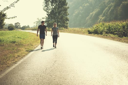 young couple enjoying in a healthy lifestyle while jogging along a country road, exercise and fitness concept