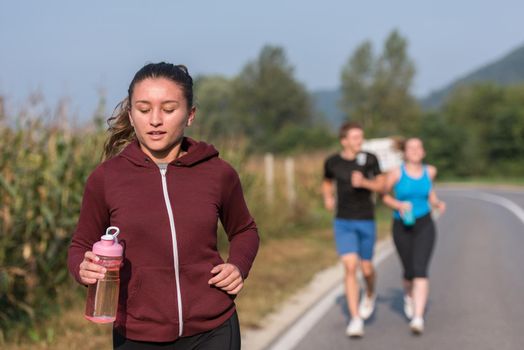 group of young people jogging on country road runners running on open road on a summer day