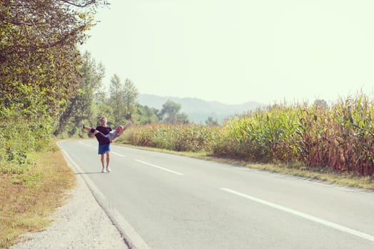 man carries a woman in his arms while jogging along a country road, exercise and fitness concept