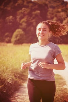 young woman enjoying in a healthy lifestyle while jogging along a country road, exercise and fitness concept