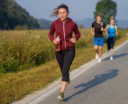 group of young people jogging on country road runners running on open road on a summer day