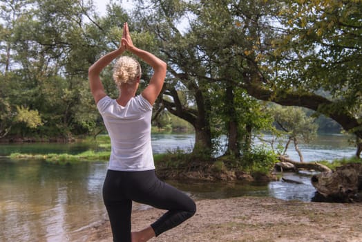 healthy woman relaxing while meditating and doing yoga exercise in the beautiful nature on the bank of the river