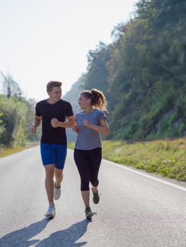 young couple enjoying in a healthy lifestyle while jogging along a country road, exercise and fitness concept