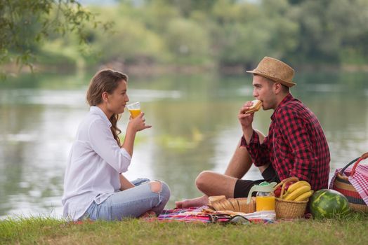 Couple in love enjoying picnic time drink and food in beautiful nature on the river bank