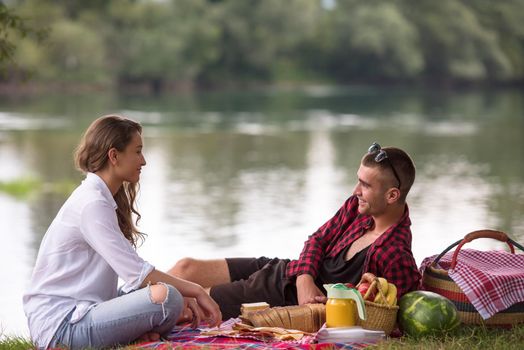 Couple in love enjoying picnic time drink and food in beautiful nature on the river bank