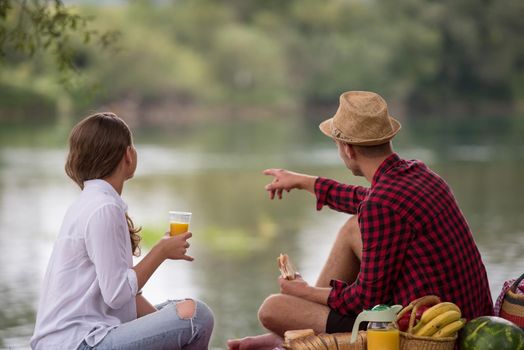 Couple in love enjoying picnic time drink and food in beautiful nature on the river bank