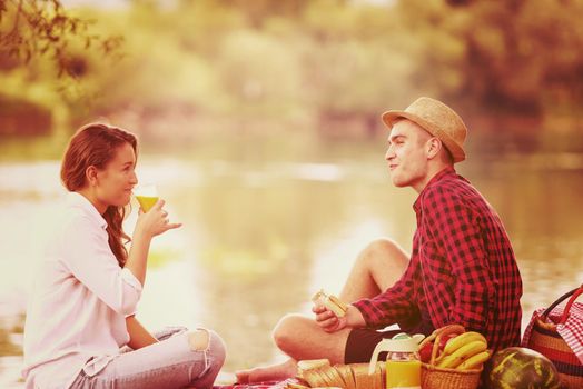 Couple in love enjoying picnic time drink and food in beautiful nature on the river bank