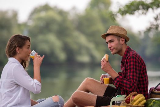 Couple in love enjoying picnic time drink and food in beautiful nature on the river bank