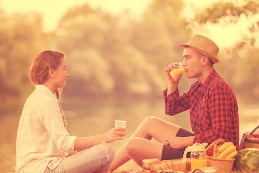 Couple in love enjoying picnic time drink and food in beautiful nature on the river bank