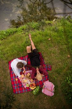 Couple in love enjoying picnic time drink and food in beautiful nature on the river bank top view