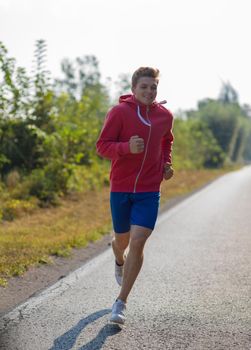 young man enjoying in a healthy lifestyle while jogging along a country road, exercise and fitness concept