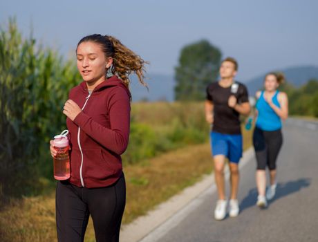 group of young people jogging on country road runners running on open road on a summer day