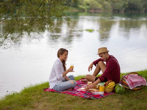 Couple in love enjoying picnic time drink and food in beautiful nature on the river bank