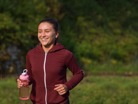 young woman enjoying in a healthy lifestyle while jogging along a country road, exercise and fitness concept