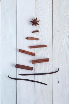 New Year spice tree made of cinnamon sticks, vanilla pods and anis star, minimalism style,, white wooden background, top view