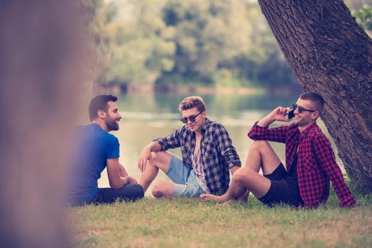 Group of young  men enjoying the nature sitting on the bank of the river