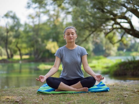 healthy woman relaxing while meditating and doing yoga exercise in the beautiful nature on the bank of the river