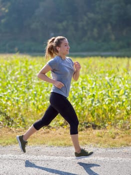 young woman enjoying in a healthy lifestyle while jogging along a country road, exercise and fitness concept