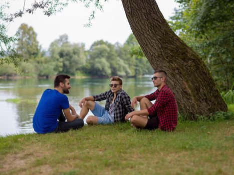 Group of young  men enjoying the nature sitting on the bank of the river