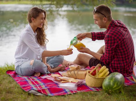 Couple in love enjoying picnic time drink and food in beautiful nature on the river bank