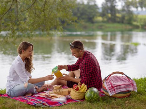 Couple in love enjoying picnic time drink and food in beautiful nature on the river bank