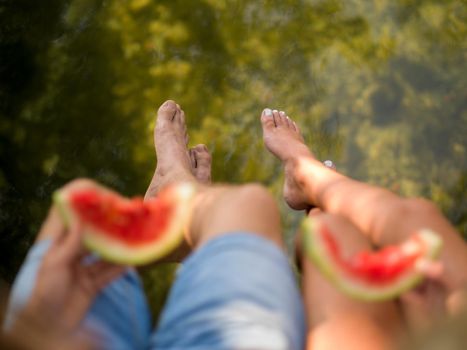 Couple in love enjoying picnic time eating watermelon in beautiful nature on the river bank