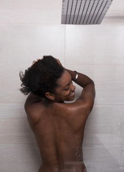 Woman in the shower,beautiful black young female showering under refreshing water, healthy lifestyle, enjoying time in luxury spa resort