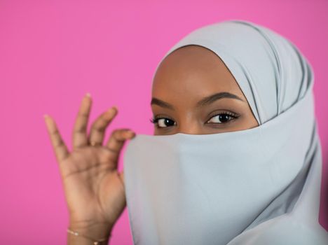 young afro beauty wearing traditional islamic clothes on plastic pink background