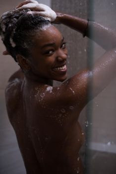 Woman in the shower,beautiful black young female showering under refreshing water, healthy lifestyle, enjoying time in luxury spa resort