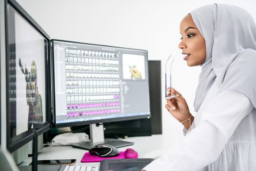 young afro american modern  muslim business woman wearing scarf on creative bright  office workplace with big screen