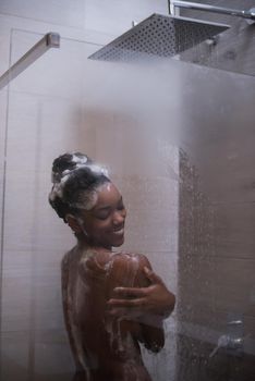 Woman in the shower,beautiful black young female showering under refreshing water, healthy lifestyle, enjoying time in luxury spa resort