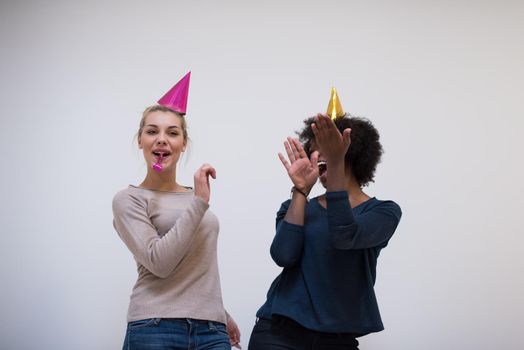 people and celebration concept  young multiethnics smiling women in party caps blowing to whistles