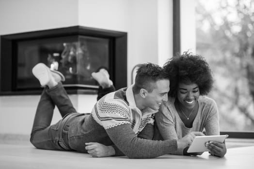 beautiful young multiethnic couple used tablet computer on the floor of their luxury home in front of fireplace autumn day