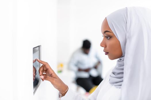 young african modern muslim woman using smart home screen control system