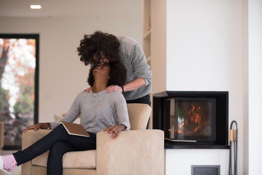 Young beautiful multiethnic couple hugging in front of fireplace at home when reading a book at autumn day